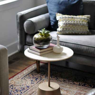 Ronde salontafel met boeken en plant naast een grijze bank