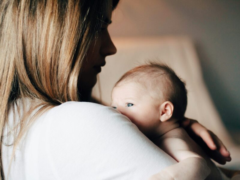 Moeder houdt een pasgeboren baby tegen zich aan