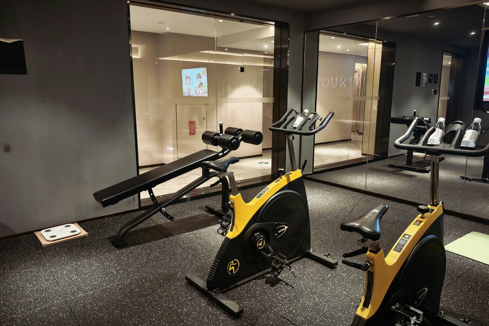 A modern gym with exercise bikes and a weight bench
