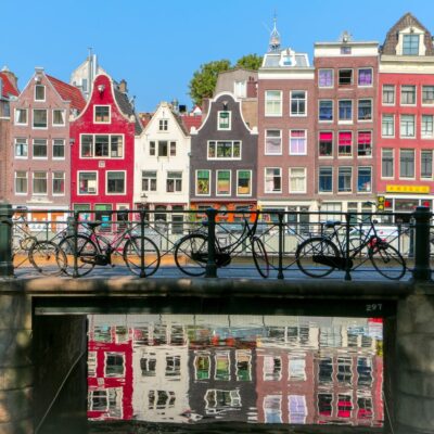 Amsterdamse gracht met woonhuizen en fietsen op de brug