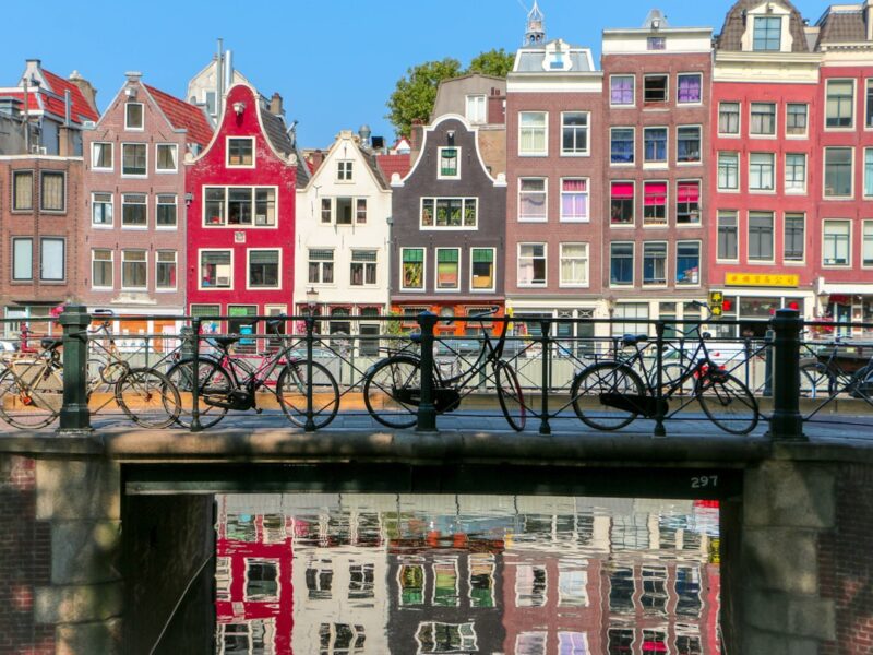 Amsterdamse gracht met woonhuizen en fietsen op de brug