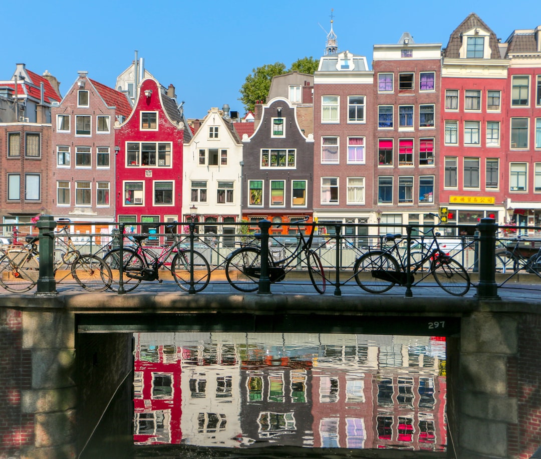 Amsterdamse gracht met woonhuizen en fietsen op de brug