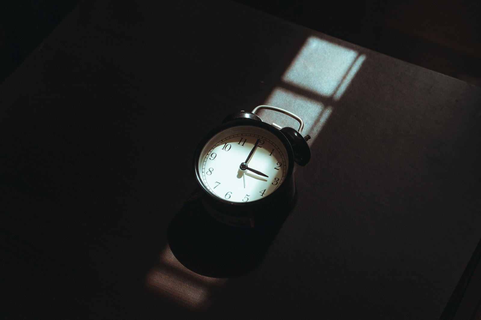 Wekker op een nachtkastje in een donkere slaapkamer op een herfstochtend