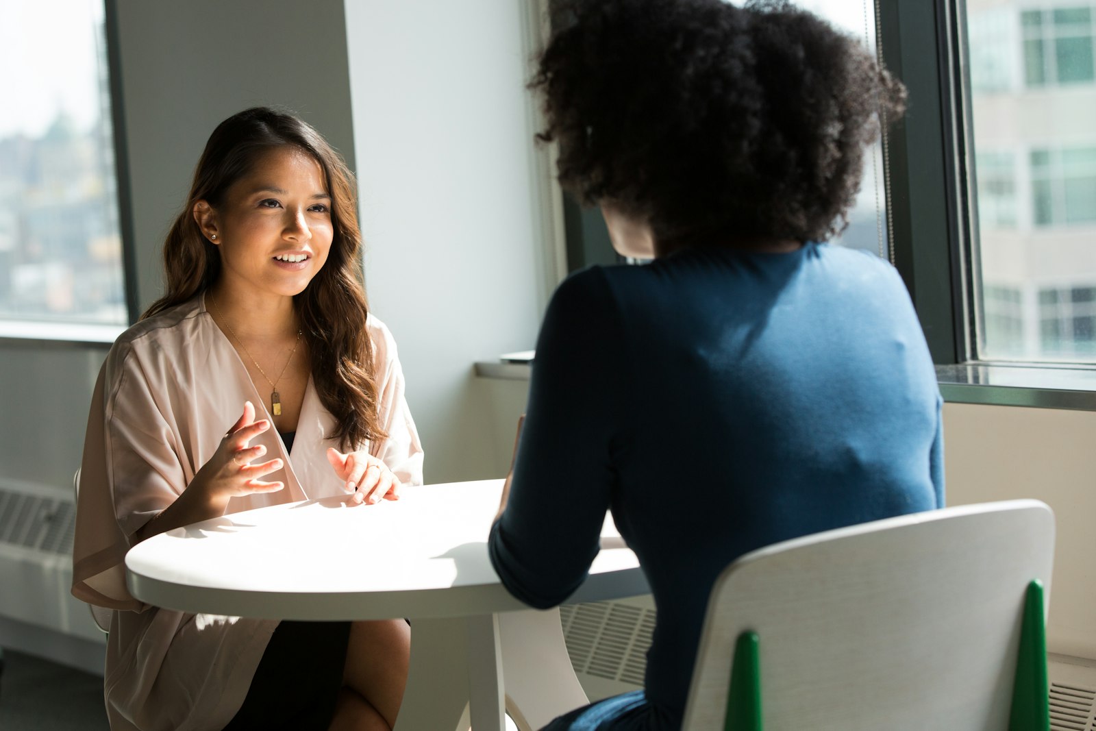 Twee collega's in een open gesprek aan een tafel met koffie