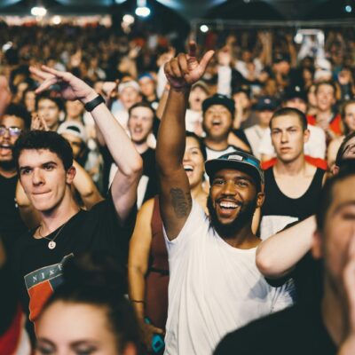 Publiek op een zonnig festivalterrein van achteren gezien