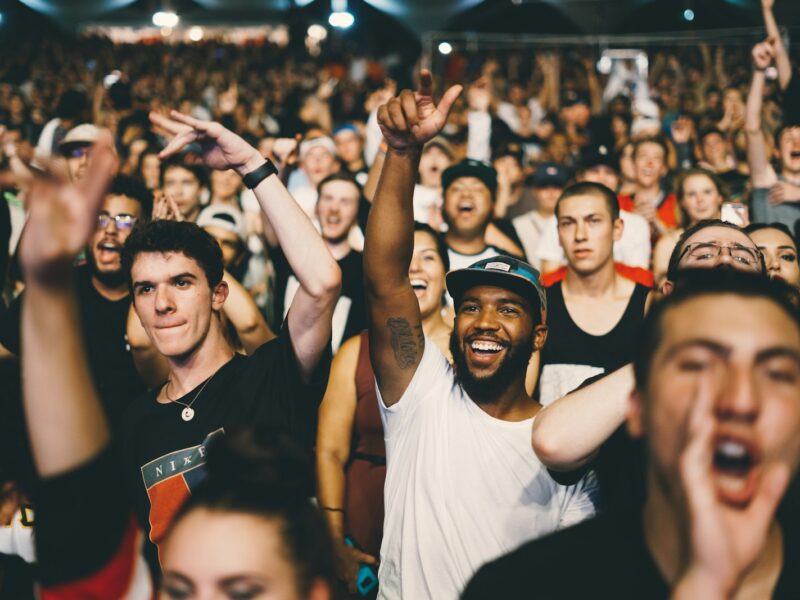 Publiek op een zonnig festivalterrein van achteren gezien