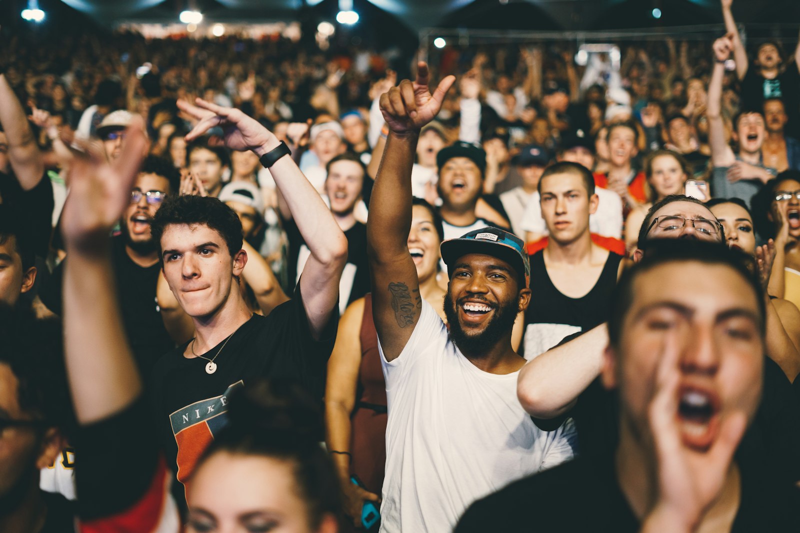 Publiek op een zonnig festivalterrein van achteren gezien