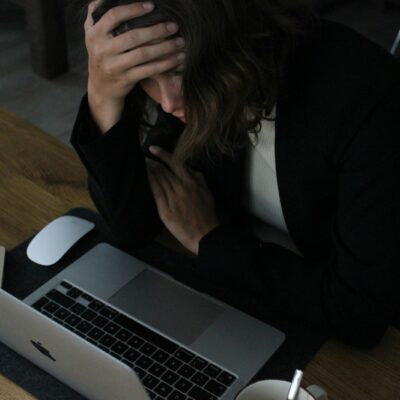 Vermoeide werknemer met het hoofd in de handen achter een laptop