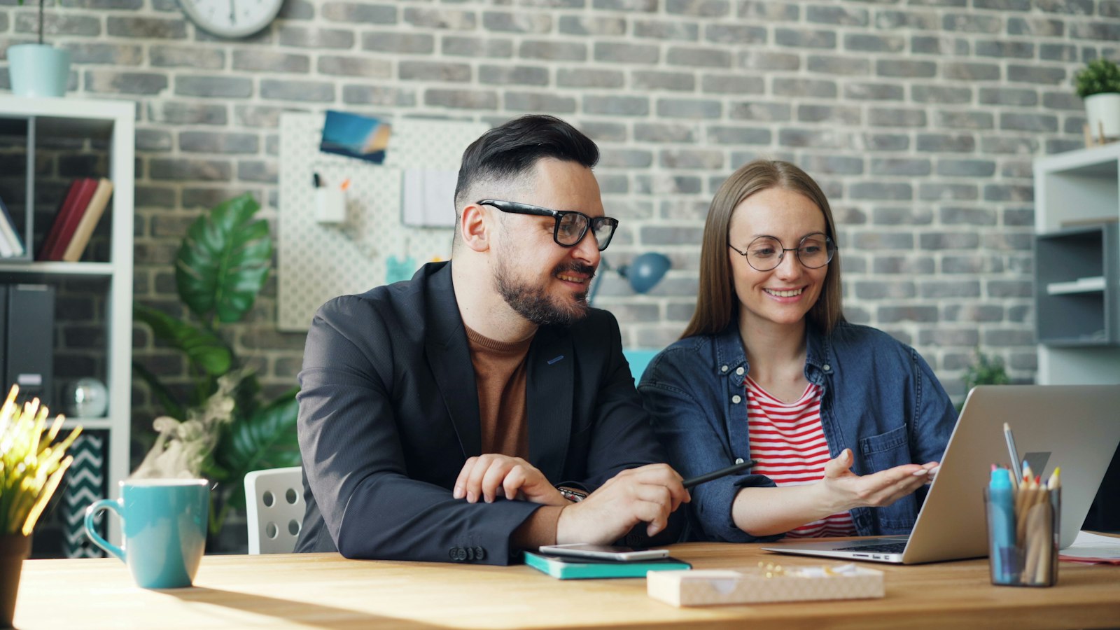 Twee collega's in gesprek aan een tafel op kantoor