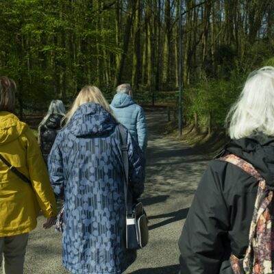 Groep volwassenen wandelt in sportkleding over een landweg
