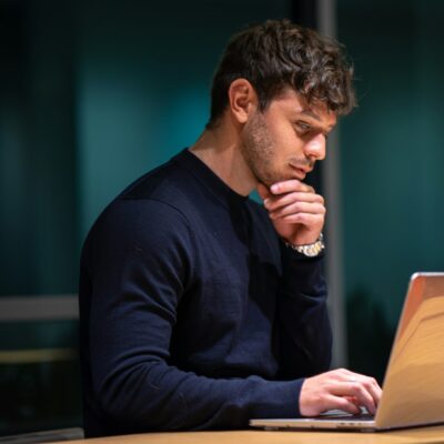 Werknemer kijkt peinzend naar het scherm van zijn laptop op kantoor