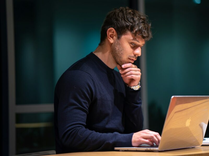Werknemer kijkt peinzend naar het scherm van zijn laptop op kantoor
