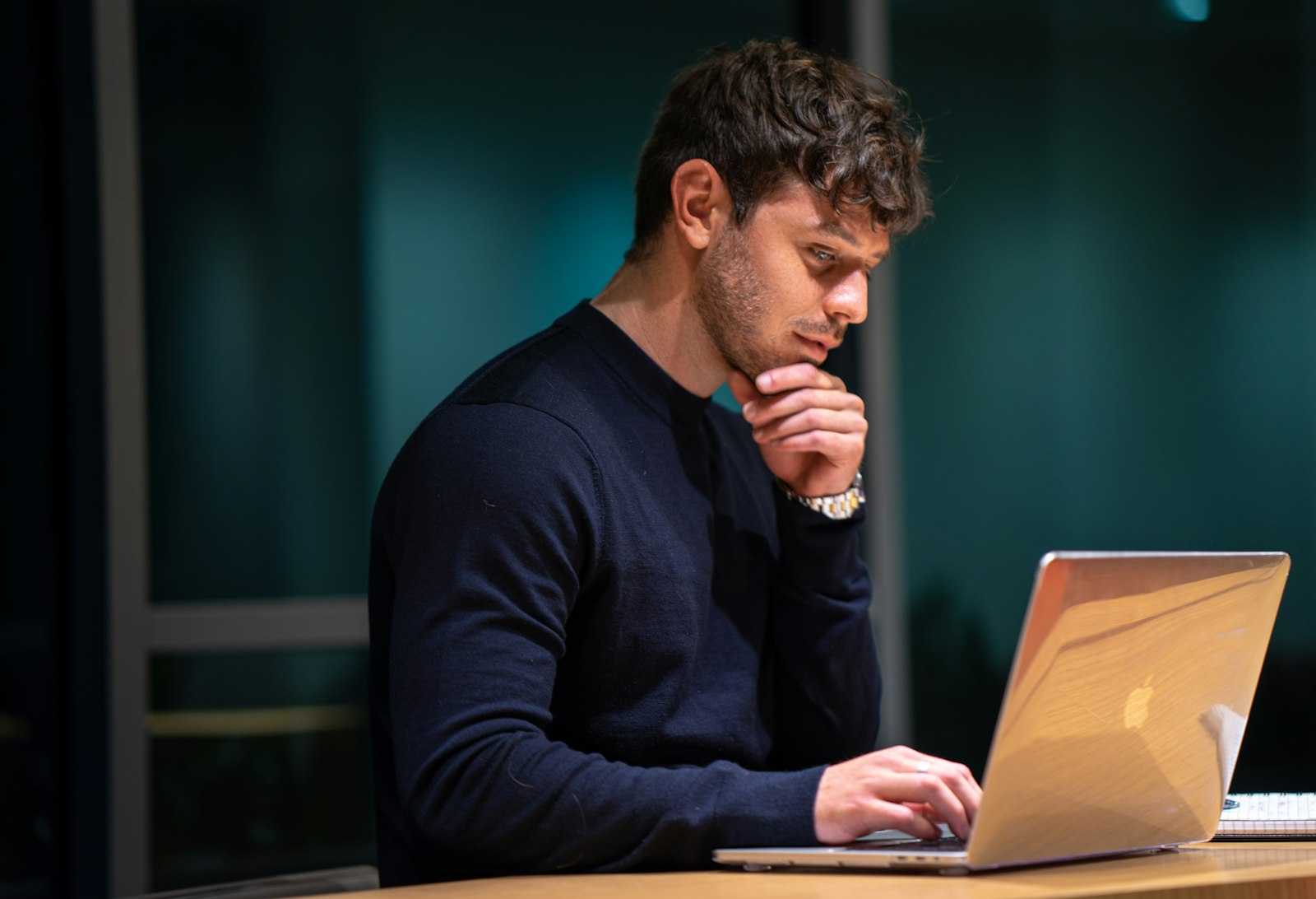 Werknemer kijkt peinzend naar het scherm van zijn laptop op kantoor