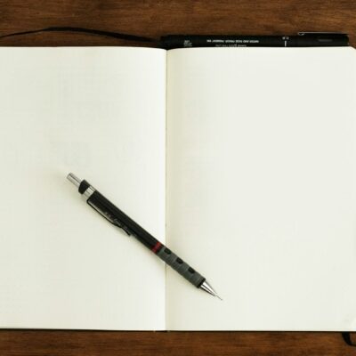 Open boek met een notitieboek en pen op tafel