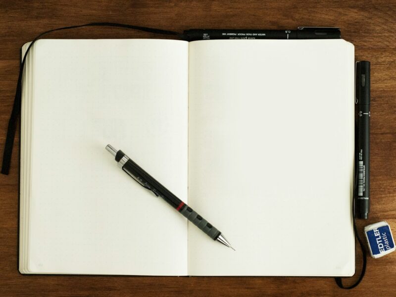 Open boek met een notitieboek en pen op tafel