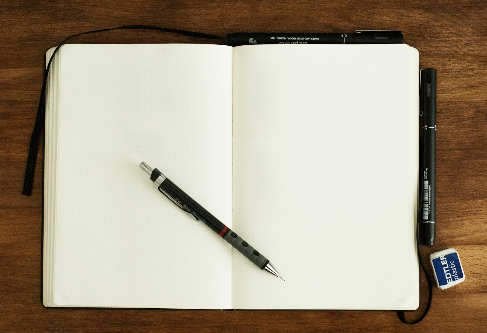 Open boek met een notitieboek en pen op tafel