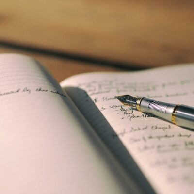Opengeslagen notitieboekje met een pen op een nachtkastje bij warm lamplicht