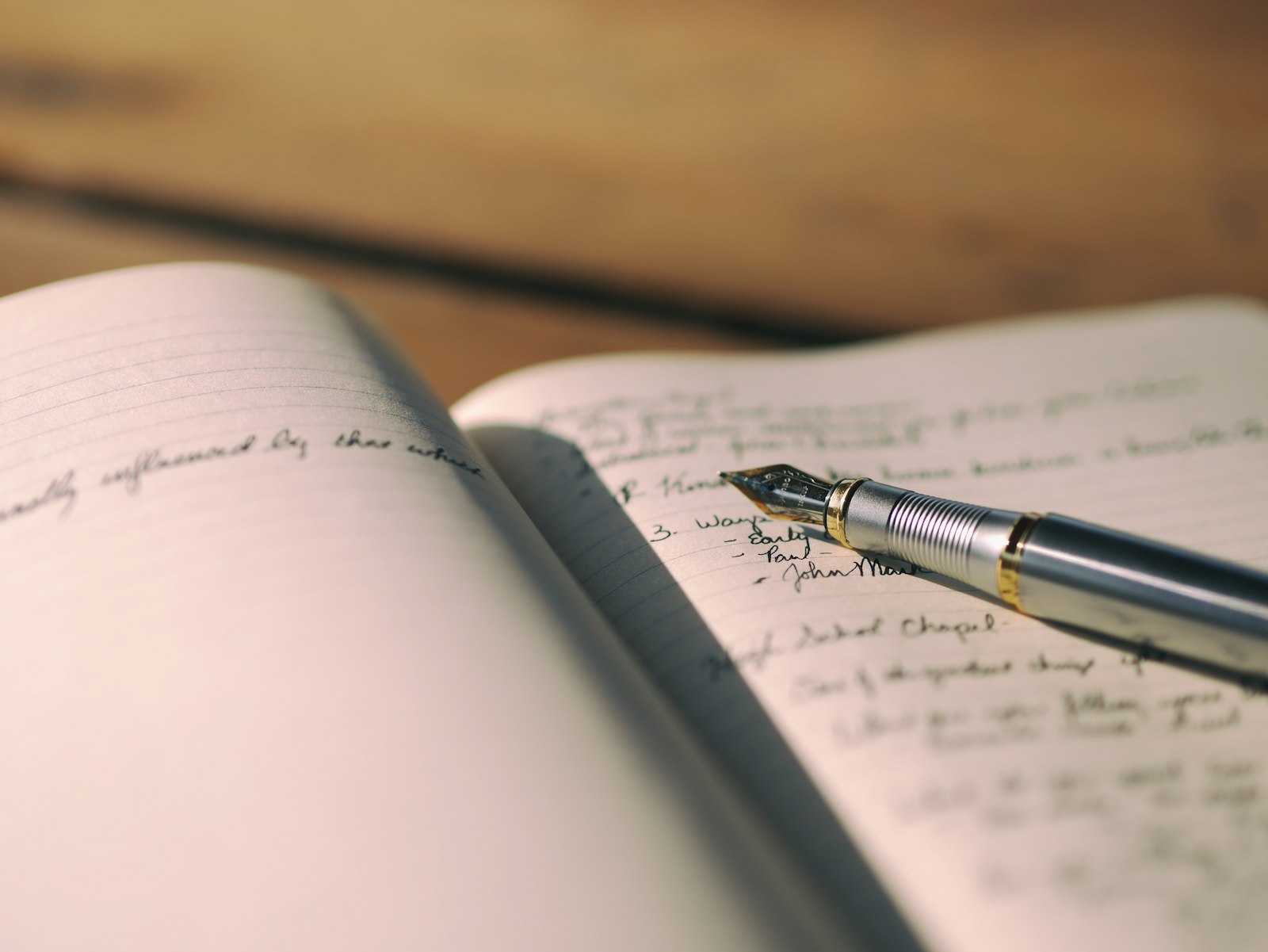 Opengeslagen notitieboekje met een pen op een nachtkastje bij warm lamplicht