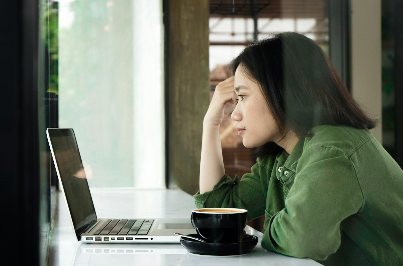 Vrouw die twijfelend naar haar laptop kijkt tijdens het werk