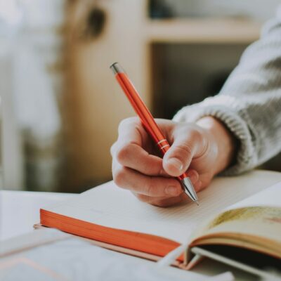 Vrouw schrijft 's avonds in een notitieboek aan tafel