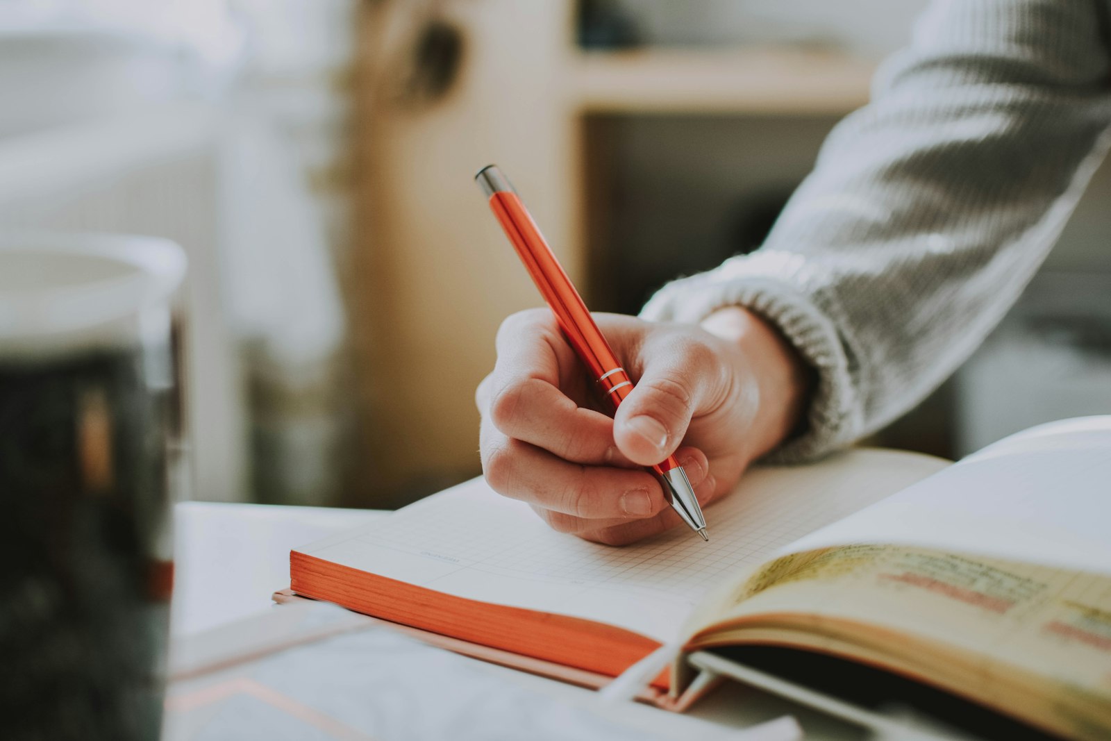 Vrouw schrijft 's avonds in een notitieboek aan tafel