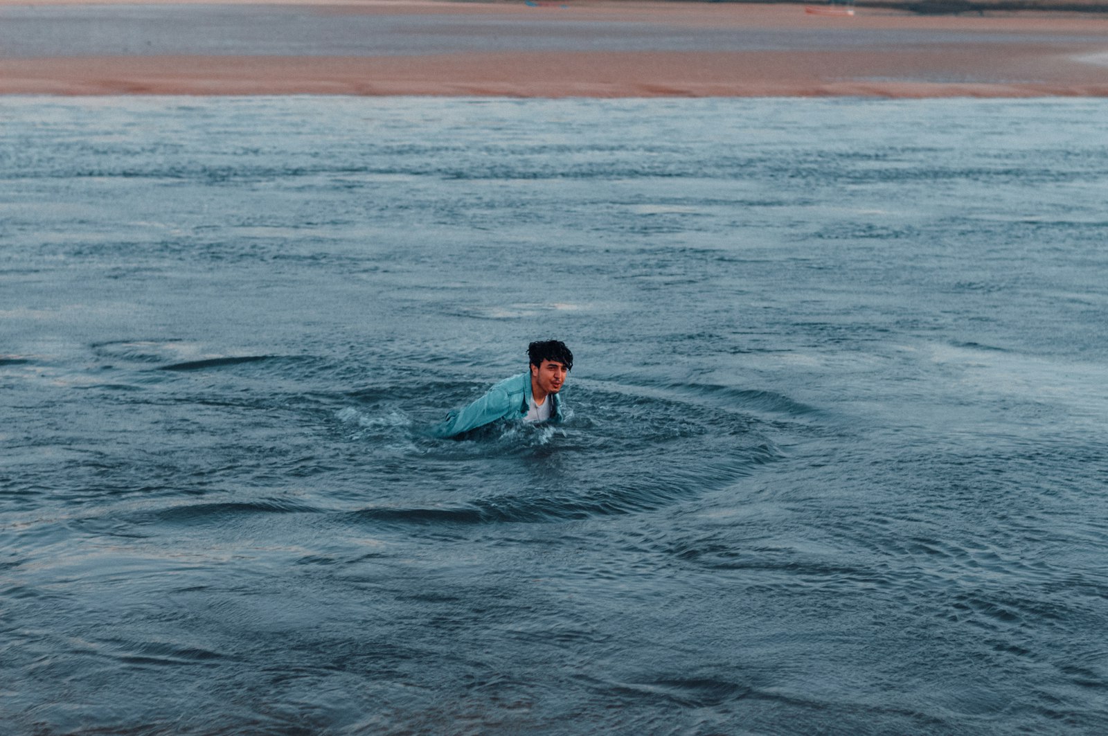 Zwemmers lopen in de herfst de zee in bij een kalm strand