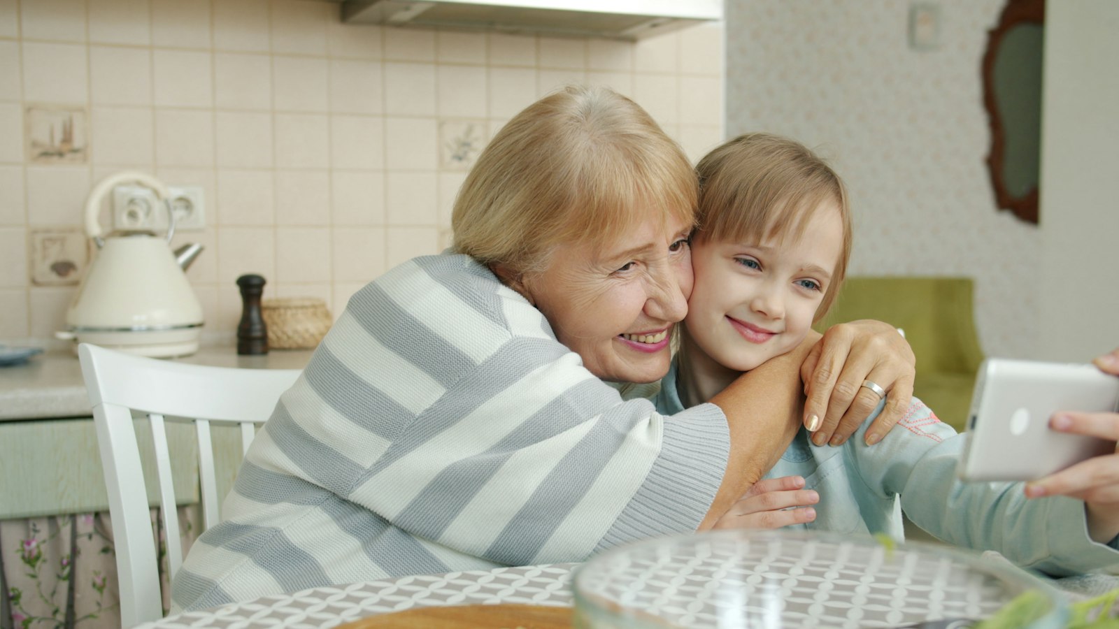 Volwassen dochter helpt haar oudere moeder met een kop thee aan tafel