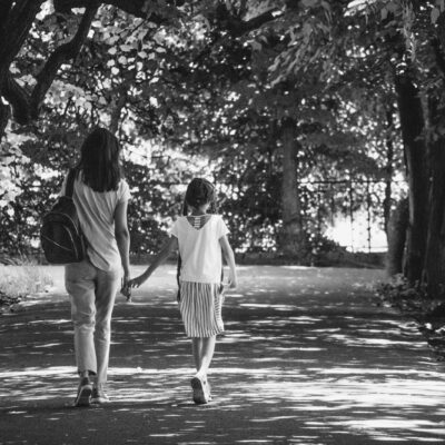 Volwassen dochter loopt arm in arm met haar oudere moeder over een pad in het park