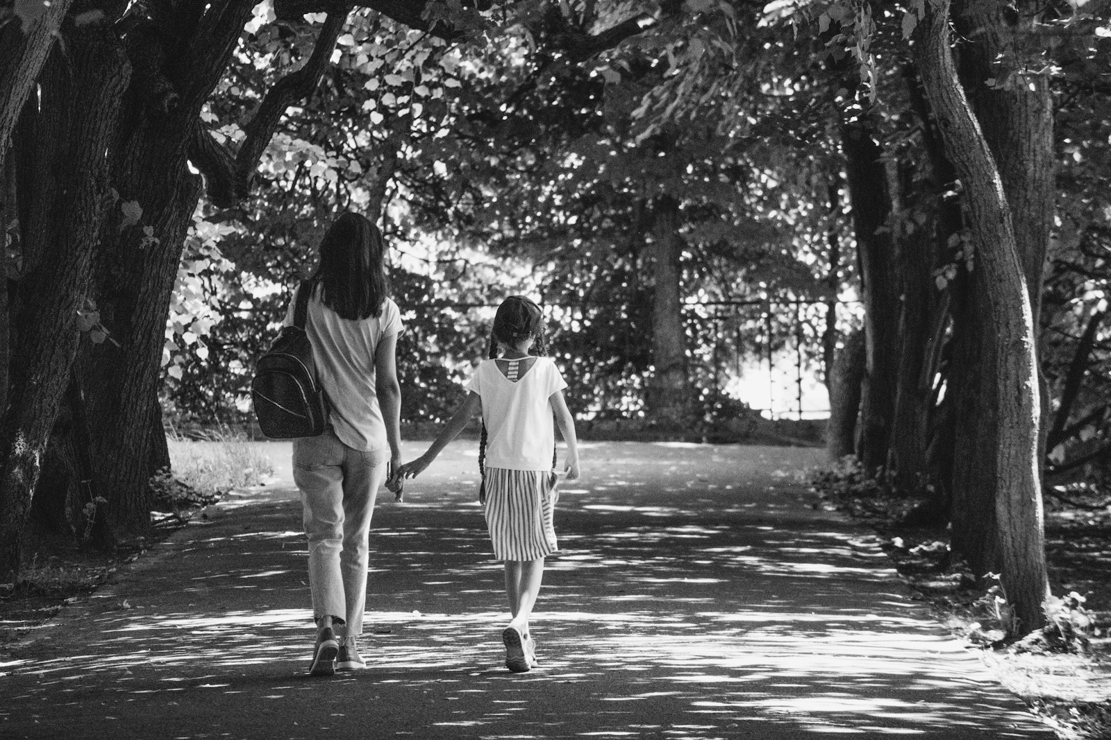Volwassen dochter loopt arm in arm met haar oudere moeder over een pad in het park