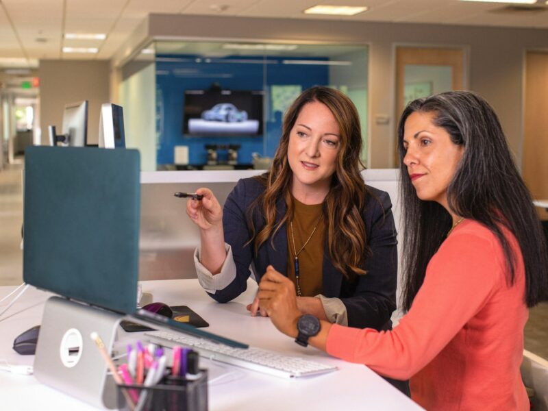 Twee collega's in een ontspannen gesprek aan een bureau op kantoor