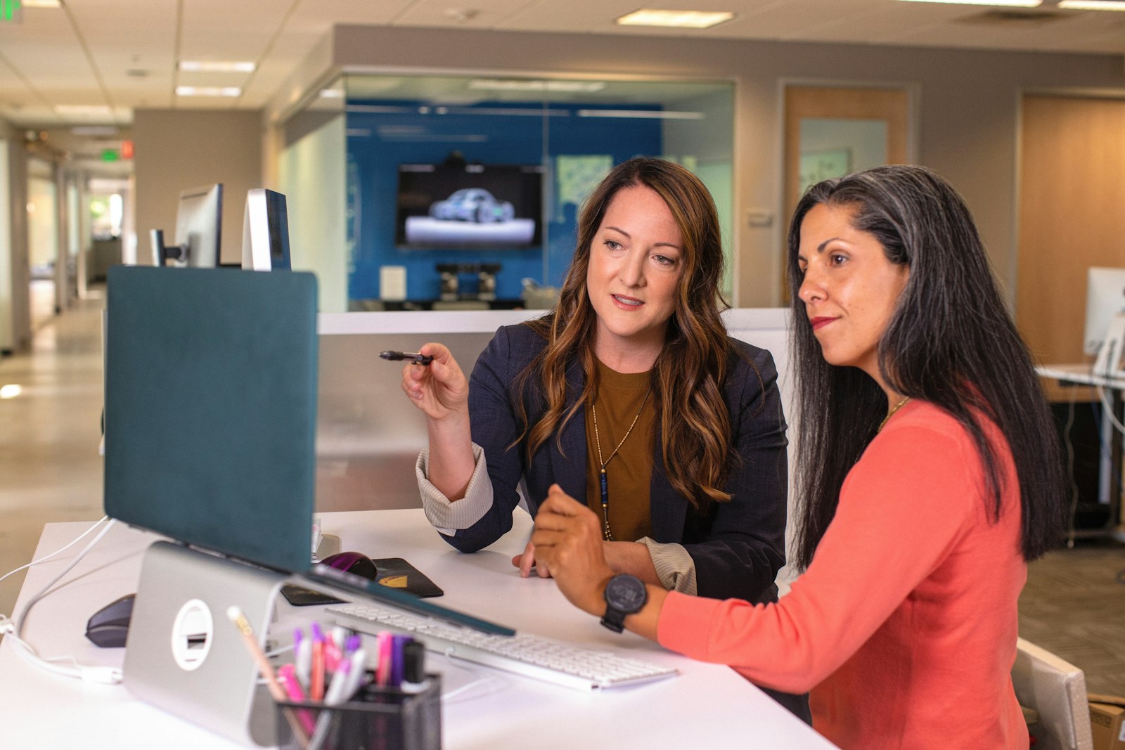 Twee collega's in een ontspannen gesprek aan een bureau op kantoor
