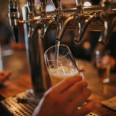 Barvrouw tapt een biertje achter de bar van een café