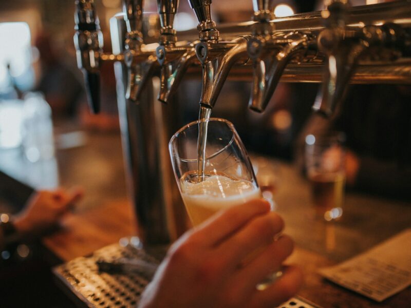 Barvrouw tapt een biertje achter de bar van een café