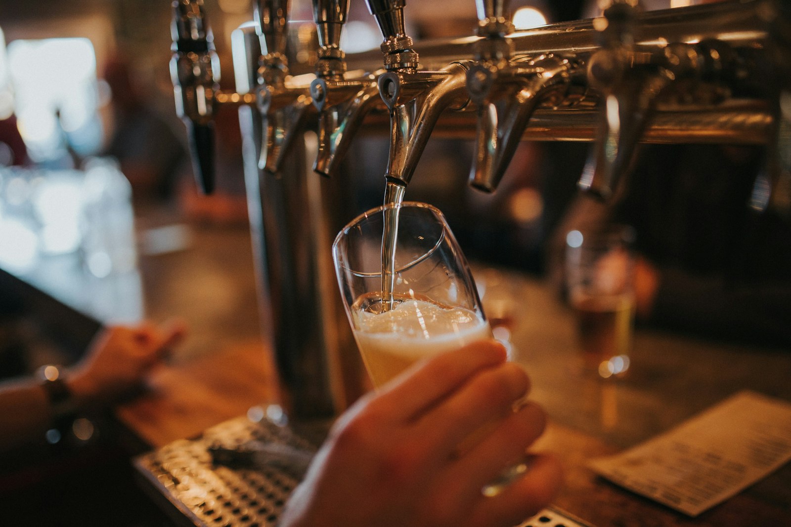Barvrouw tapt een biertje achter de bar van een café