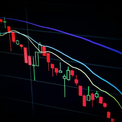 Munten en een koersgrafiek van cryptovaluta op een scherm