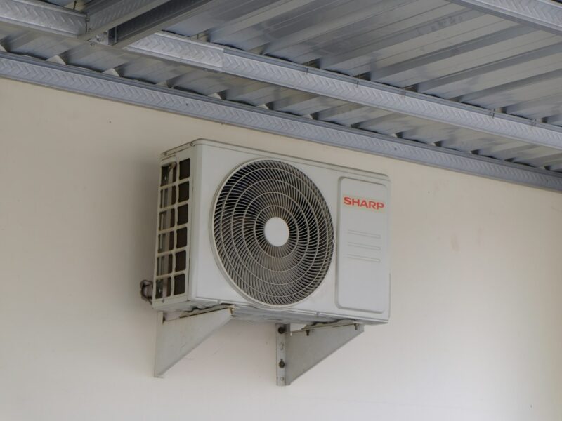 Monteur installeert de buitenunit van een warmtepomp bij een woning