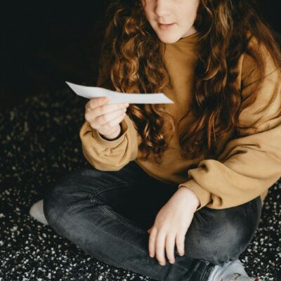Vrouw zit vermoeid aan een keukentafel met een brief en een kop thee