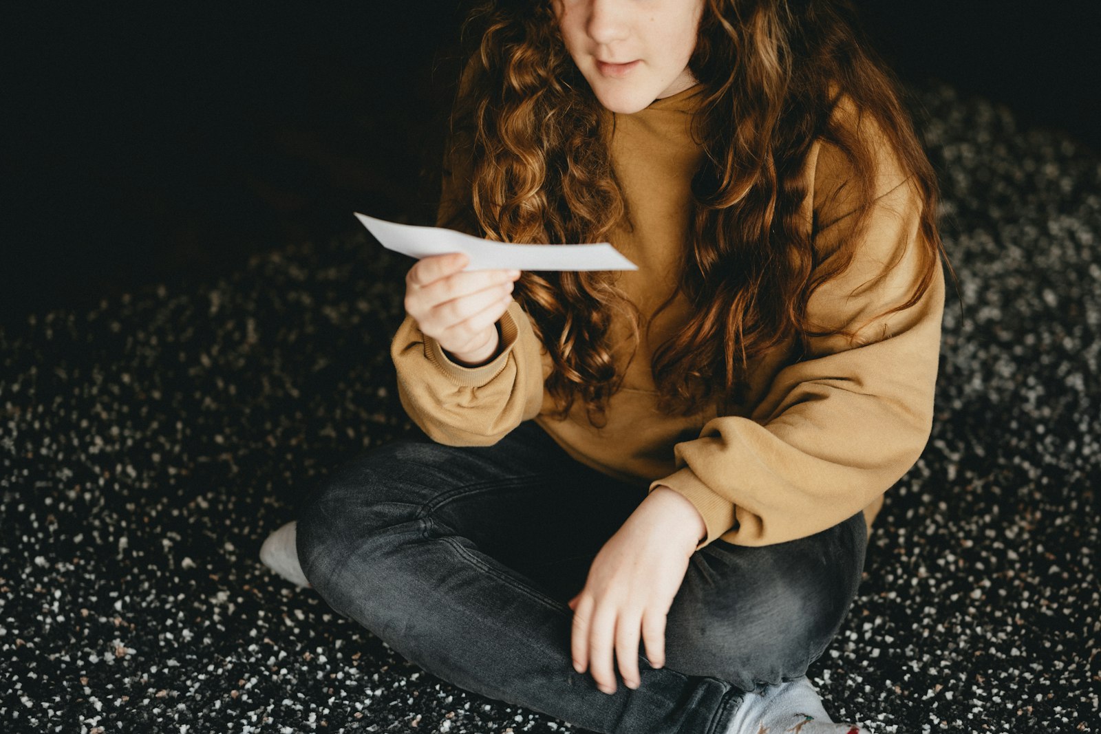 Vrouw zit vermoeid aan een keukentafel met een brief en een kop thee