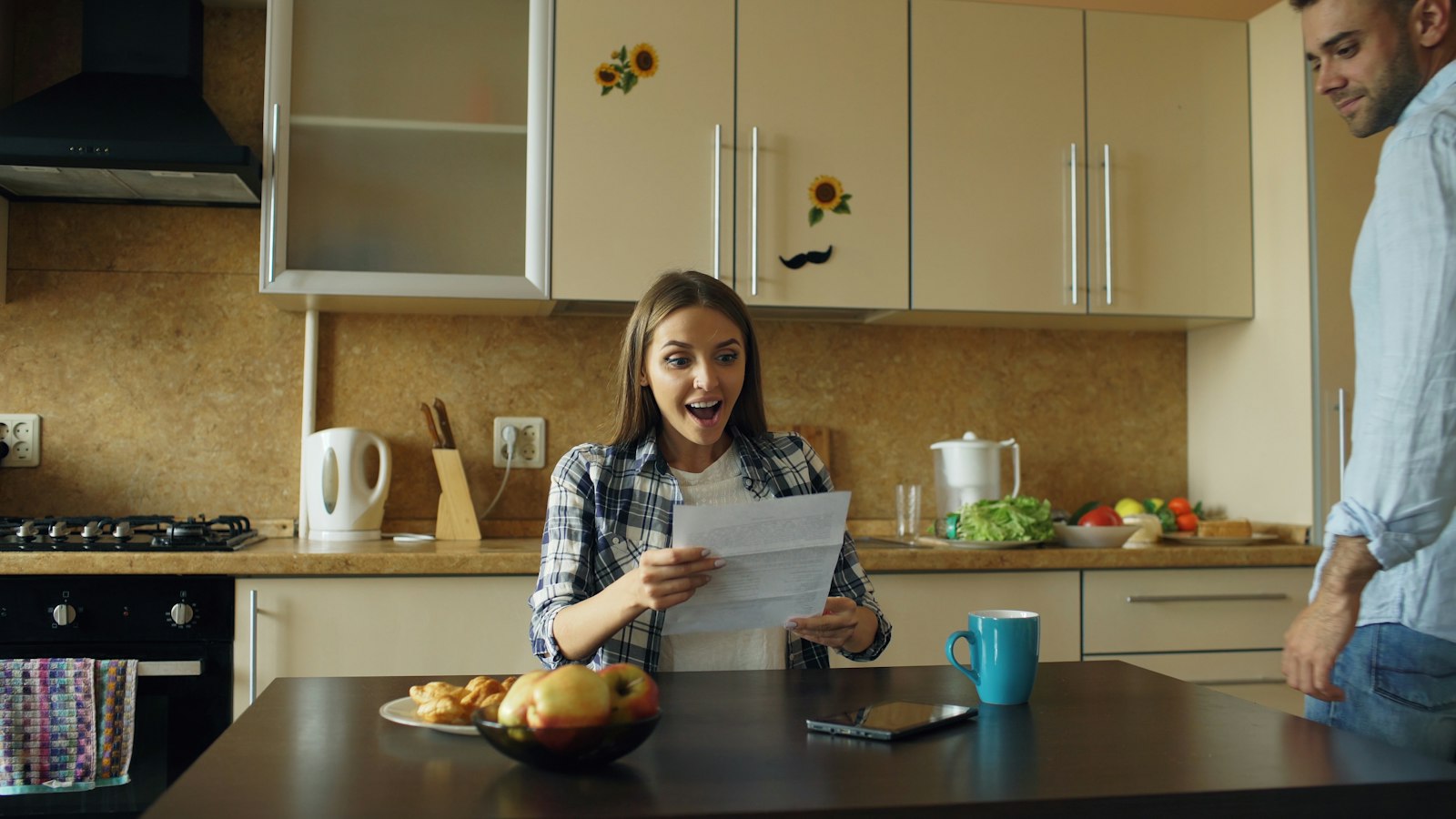 Iemand bekijkt aan de keukentafel een pensioenoverzicht op papier en laptop