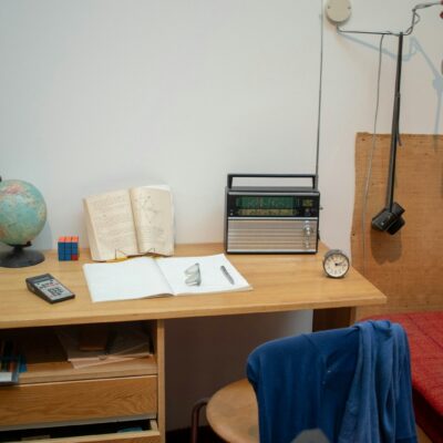 Student achter een bureau vol papieren die gefrustreerd naar een laptop kijkt