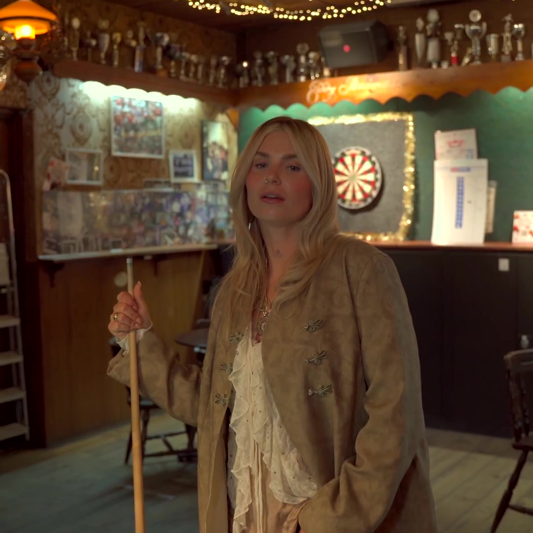 Roxeanne Hazes met een keu in een bruin café in de clip van Tranen in de giftshop