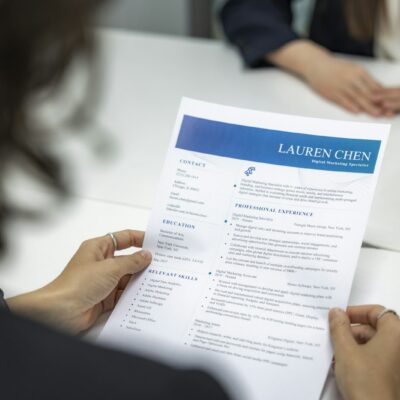 Twee mensen in gesprek aan een tafel met een cv en een laptop