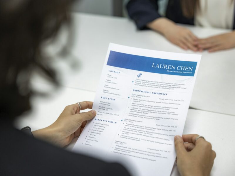 Twee mensen in gesprek aan een tafel met een cv en een laptop