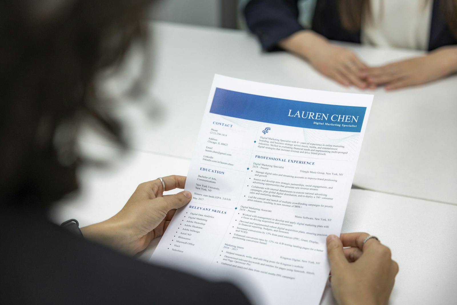 Twee mensen in gesprek aan een tafel met een cv en een laptop