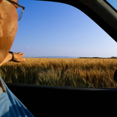 Oudere automobilist kijkt in de achteruitkijkspiegel van zijn auto
