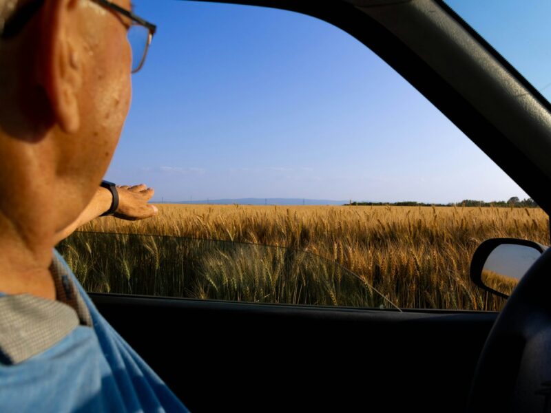 Oudere automobilist kijkt in de achteruitkijkspiegel van zijn auto