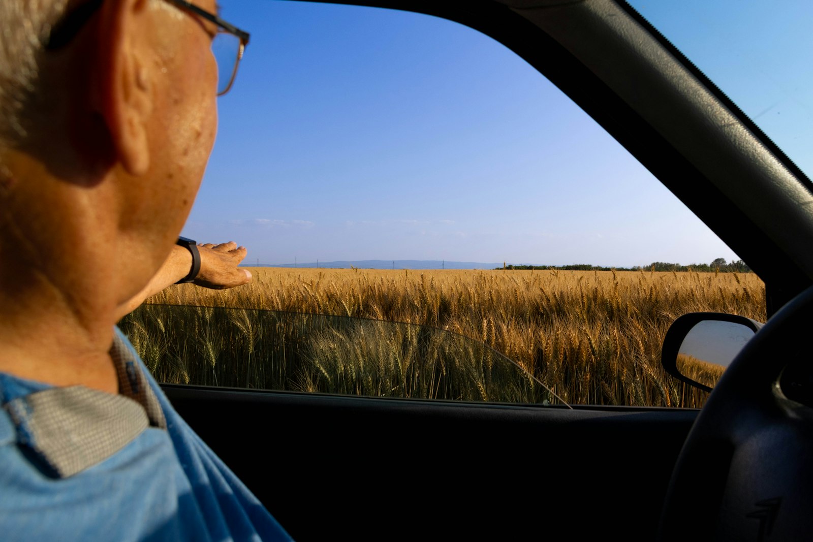 Oudere automobilist kijkt in de achteruitkijkspiegel van zijn auto
