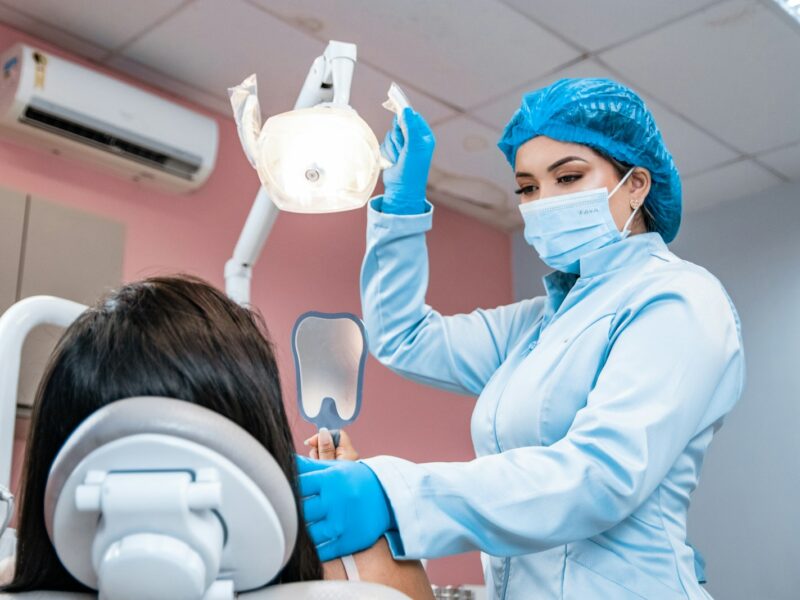 Mondhygiënist behandelt een patiënt in de stoel van een tandartspraktijk