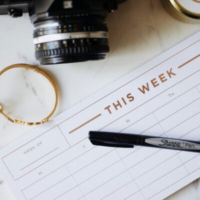 Een opengeslagen weekagenda met ingekleurde tijdblokken op een bureau