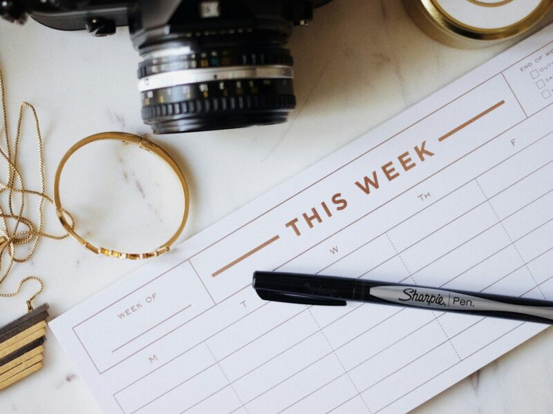 Een opengeslagen weekagenda met ingekleurde tijdblokken op een bureau